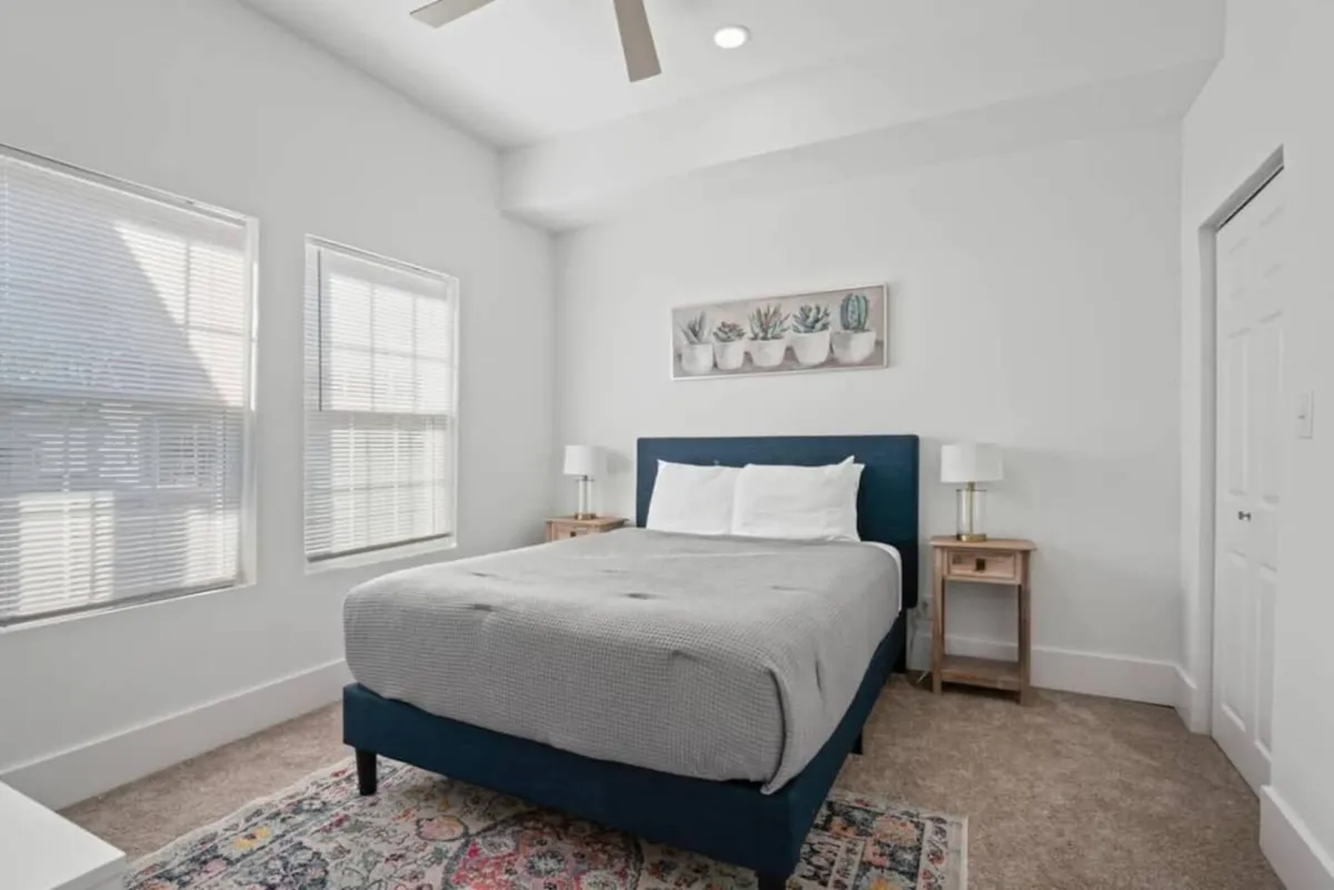 A tranquil bedroom with a plush bed, soft bedding, stylish nightstands, calming wall art, and ample natural light from generous windows, creating an inviting and restful atmosphere.