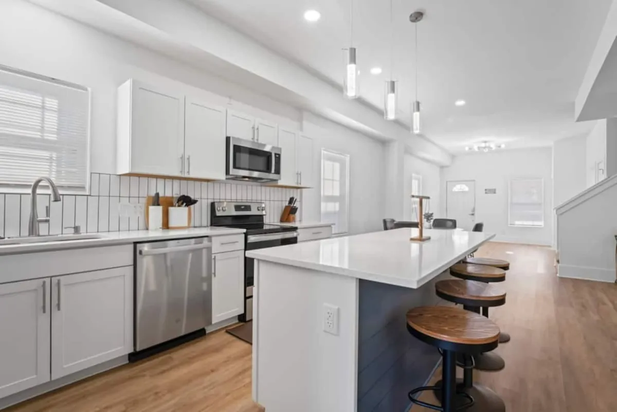 A bright, welcoming kitchen featuring a central island with bar stools, sleek stainless steel appliances, and modern cabinetry. The open space is designed for both cooking and entertaining, allowing for casual conversations while preparing meals.