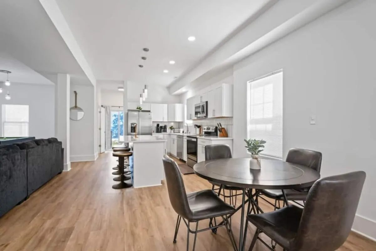 An inviting open-plan space combining a kitchen island, a spacious dining table, and contemporary seating. Modern appliances and thoughtful lighting create a stylish, functional atmosphere ideal for group dining and socializing.