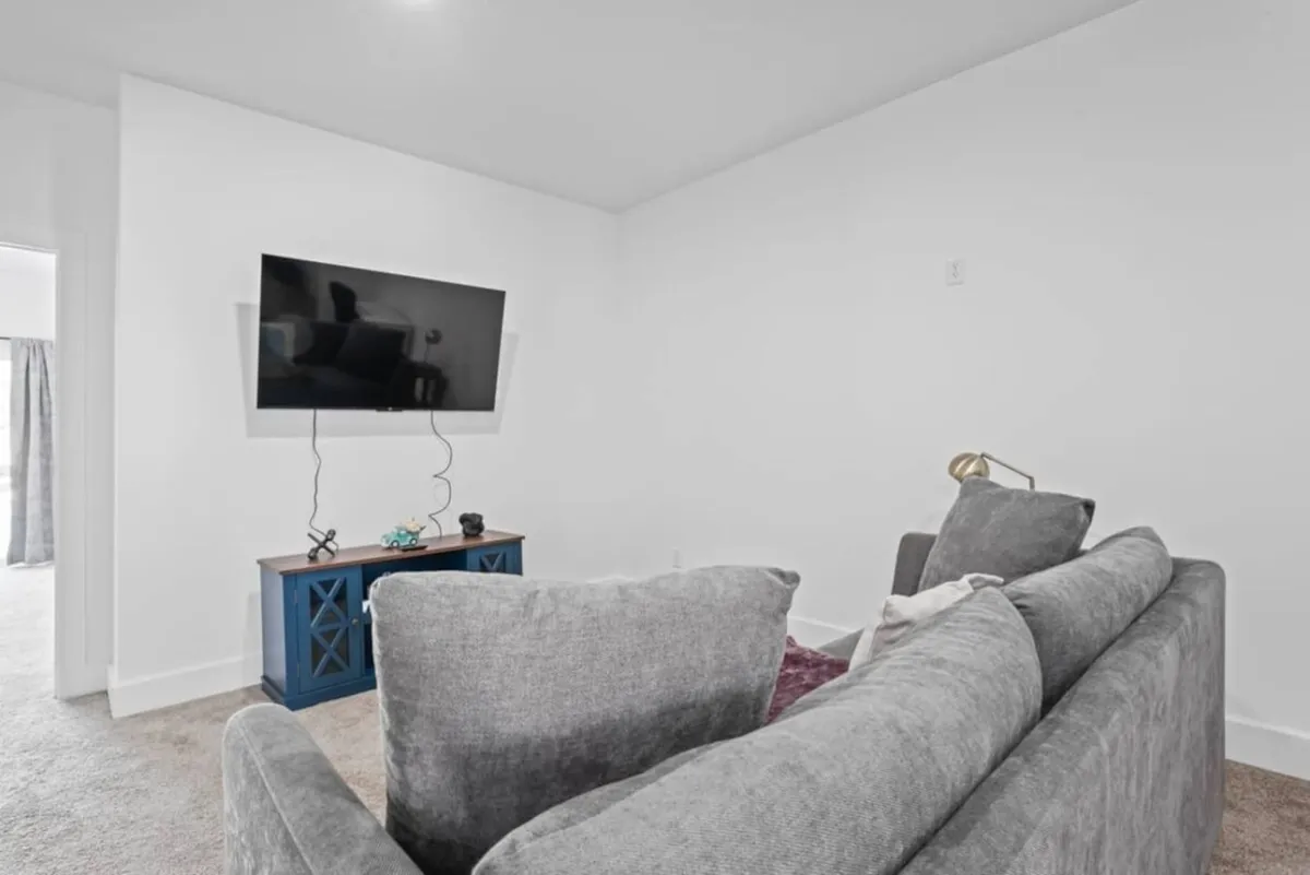 A comfortable living room with a plush sofa facing a television and a stylish blue console table. The arrangement invites guests to gather for movie nights, streaming sessions, or relaxed socializing, with décor that feels both contemporary and cozy.